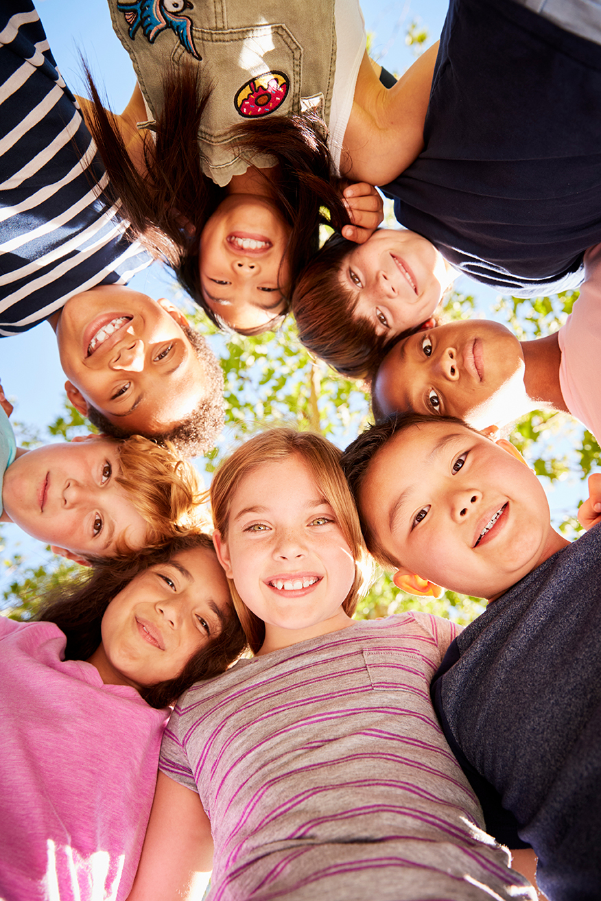 Group of kids outdoors looking down at camera